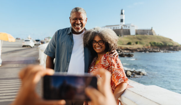 快乐的黑人情侣在海边微笑着摆姿势拍摄度假照片图片下载