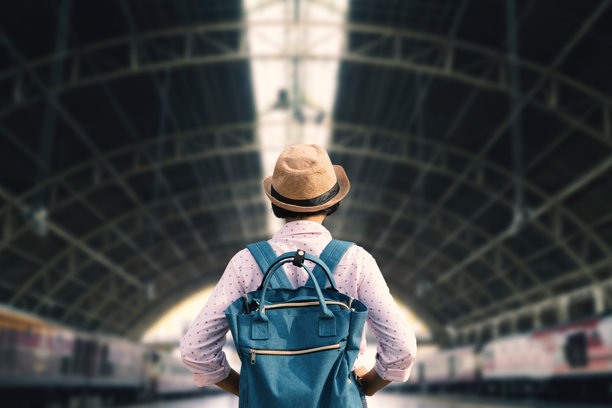 戴着帽子背着背包站在火车站的男人的后视图图片下载