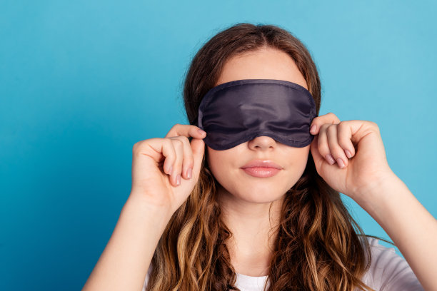 可爱漂亮的女孩穿着白色时尚睡衣，特写照片，背景为蓝色。图片下载