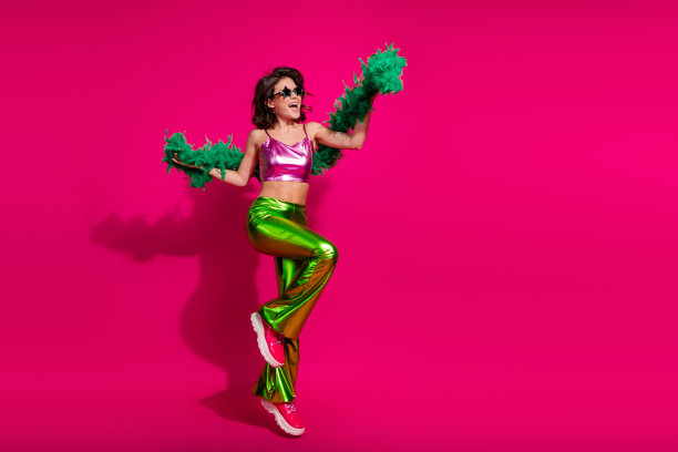 充满活力的迪斯科主题照片，展示了一位时尚年轻女性穿着色彩斑斓、复古风格的服装，在鲜艳的洋红色背景下跳舞。图片下载