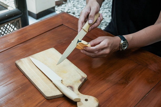 特写照片：男人在厨房桌子上用特殊刀具磨刀器磨刀。图片下载