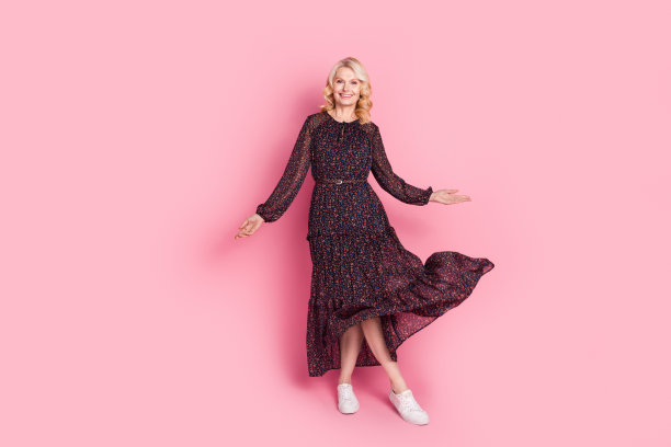 优雅的老年女士在粉色背景上舞动着裙子的大尺寸照片图片下载