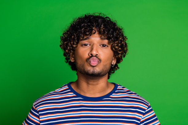 穿着时尚条纹衣服的友善幽默男士在绿色背景上送吻的照片图片下载