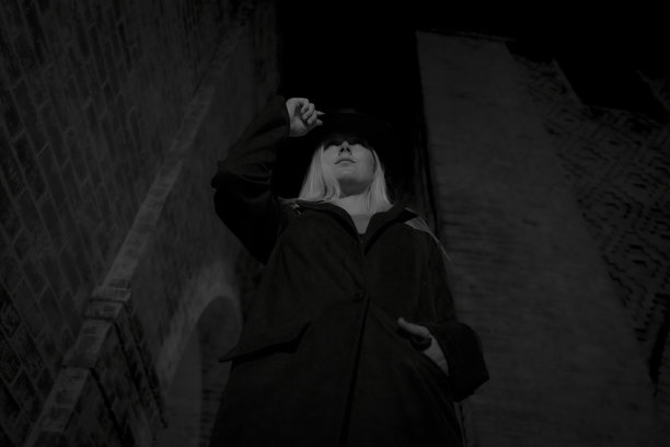 夜晚年轻金发女士戴帽子的黑白单色照片的仰拍角度图片下载