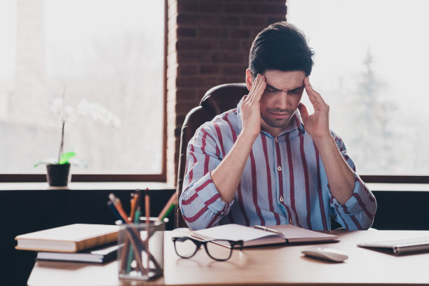 年轻男性企业员工在现代办公室家中室内穿着条纹衬衫感到头痛的照片图片下载