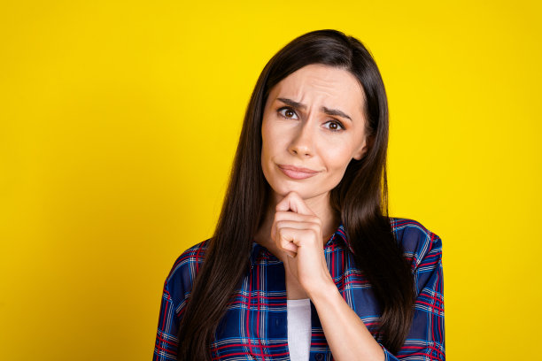 可爱的年轻女士的照片肖像，表情困惑和怀疑，穿着时尚的格子服装，背景为黄色。图片下载