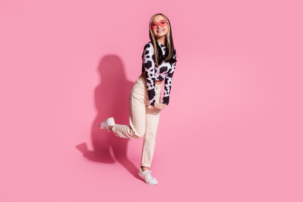 穿着牛皮衬衫的快乐漂亮女士在粉色背景下的空旷空间中跳舞的全身照片图片下载
