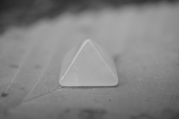 一座小型装饰性金字塔放在秋天的叶子上。黑白照片。图片下载