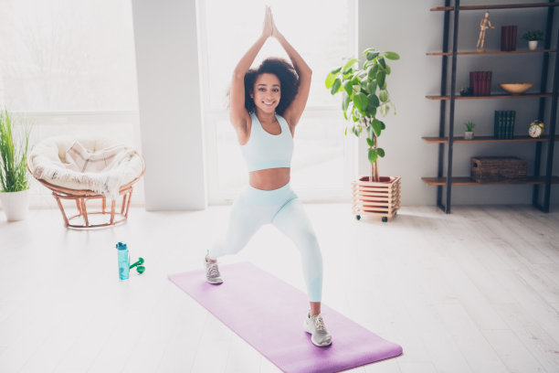 全身照片，纤细可爱的女性穿着运动服在室内公寓房间享受瑜伽。图片下载