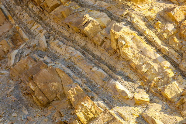 这张照片展示了一块特写的岩石，层次分明。岩石呈浅黄色，带有深色条纹，形成了典型的层状图案。图片下载