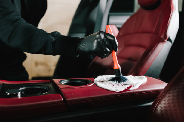 洗车工在服务站用泡沫清洁剂给汽车的红色皮革内饰进行清洗。汽车美容过程中使用泡沫清洁皮革内饰。图片下载