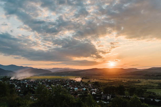 春天的村庄日落。乡村风景，田野与山脉。适合用作背景的照片，展现村庄和阳光的景色。图片下载