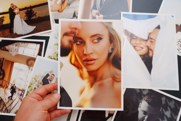 女性的手放在桌子上展示婚礼照片。图片下载