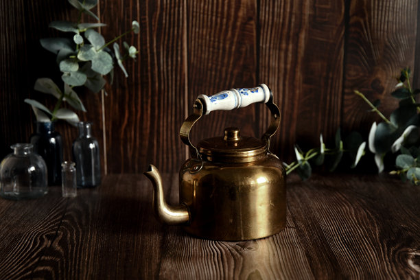 这张照片展示了一个金色的茶壶，白色把手上装饰着蓝色图案。图片下载