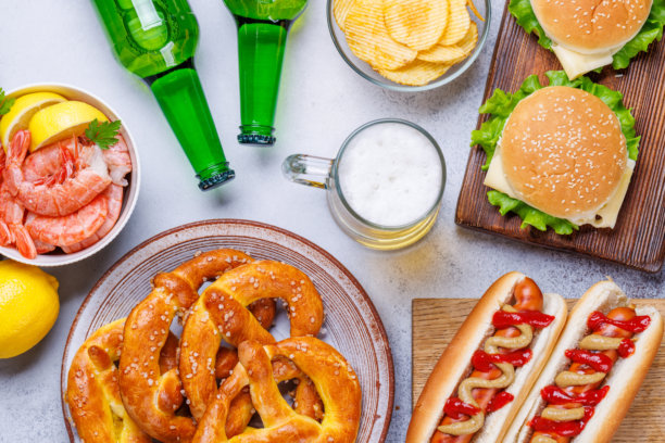 一张生动的照片，展示了一杯啤酒，周围是各种小吃和快餐。图片下载