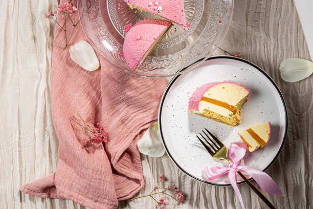 粉色天鹅绒慕斯蛋糕，切开后露出芒果慕斯和百香果，放在玻璃蛋糕盘上。低卡路里慕斯甜点。侧面视图。平铺拍摄。高质量照片。图片下载