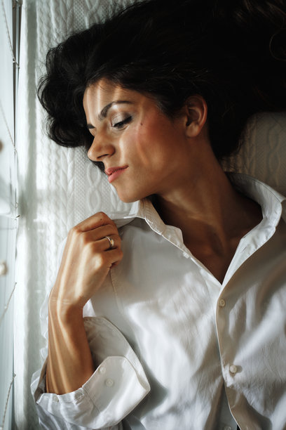 阳光透过百叶窗照射在一位美丽年轻女性的躺姿照片。图片下载