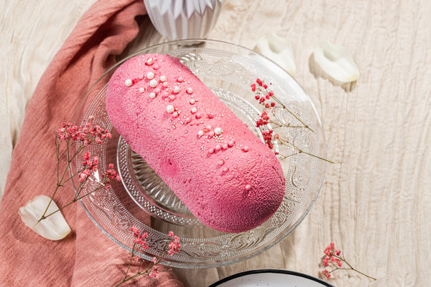 粉色天鹅绒慕斯蛋糕，装饰有甜美的珍珠，放在玻璃蛋糕盘上。低卡路里慕斯甜点。芒果和百香果慕斯蛋糕。侧面视图。平铺拍摄。高质量照片。图片下载