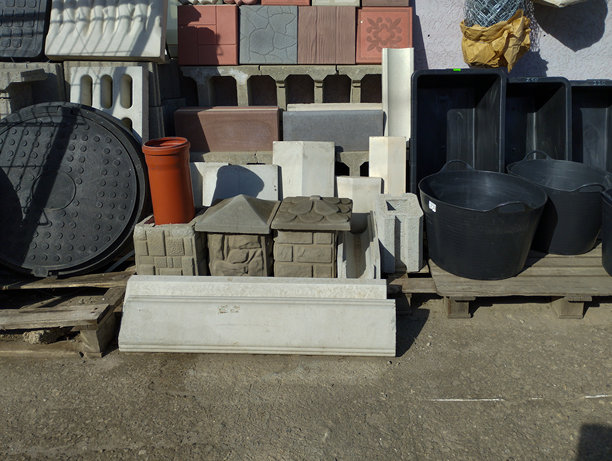 这张照片捕捉了各种建筑材料在户外排列的场景。构图中央是两座迷你装饰房屋，采用石砌和瓦屋顶。图片下载