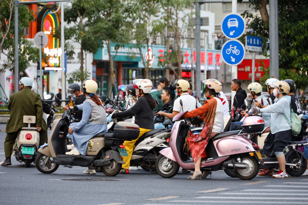 中国人在城市街道上骑摩托车，海南岛上的电动车图片下载