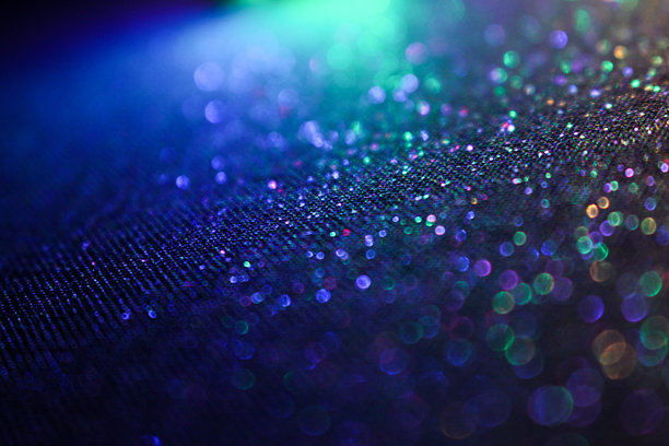 一张浅景深的照片，展示了多彩的抽象闪光背景，鲜艳的霓虹灯光映衬在黑色背景上。图片下载