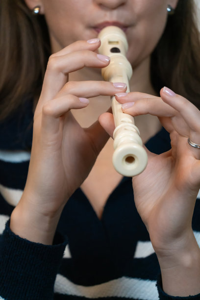 特写镜头下，一位女性音乐家热情地演奏着直笛，巧妙地创造出迷人的旋律，展现了音乐表达和艺术的美。竖版照片图片下载