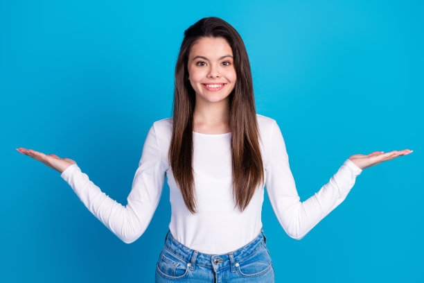 可爱的少女在蓝色背景下穿着时尚的白色服装，手中比划着空白空间的照片肖像。图片下载