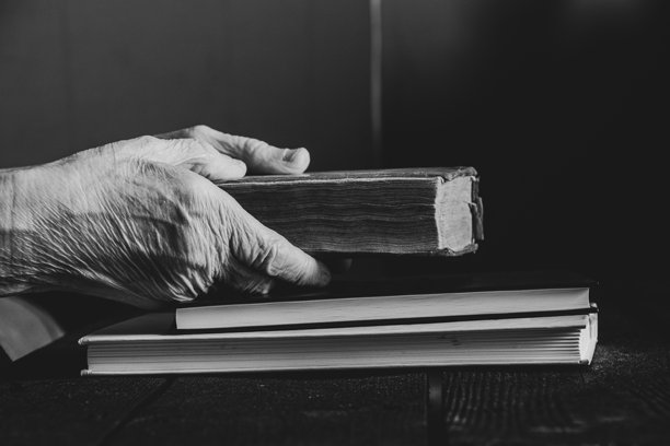 老年女性在家中桌子旁阅读书籍，黑白照片图片下载