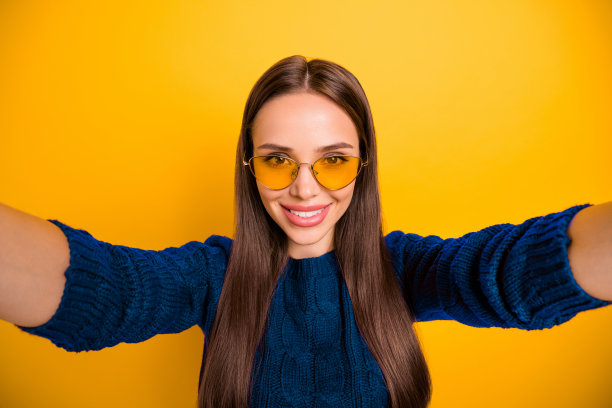 特写照片，快乐的女孩穿着玛莎拉色毛衣，微笑着拍照，背景为黄色。图片下载