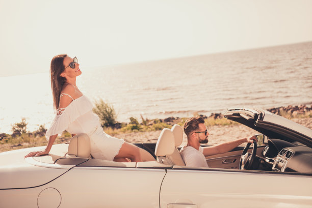 穿着白色衣服的甜蜜迷人的已婚夫妇在乡间道路上开车微笑的照片图片下载