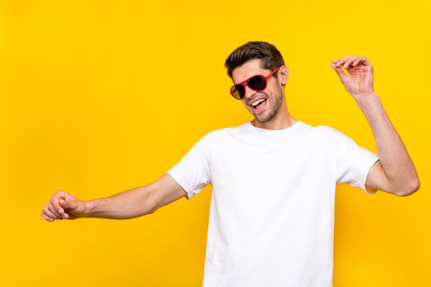 搞笑的年轻棕发男孩穿着眼镜和T恤在黄色背景上跳舞的照片图片下载