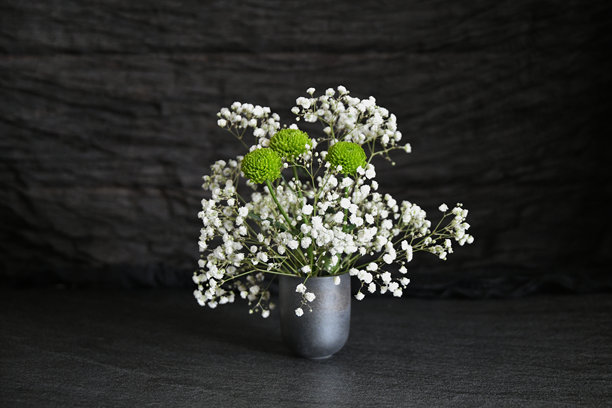 这张照片展示了一个小灰色花瓶中装有满天星花和绿色菊花的组合。图片下载