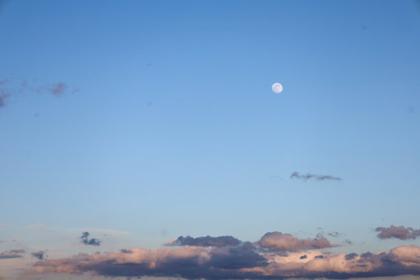 这张照片捕捉了清澈的蓝天，底部有小积云。在天空的中央，可以看到一轮淡淡的月亮。图片下载