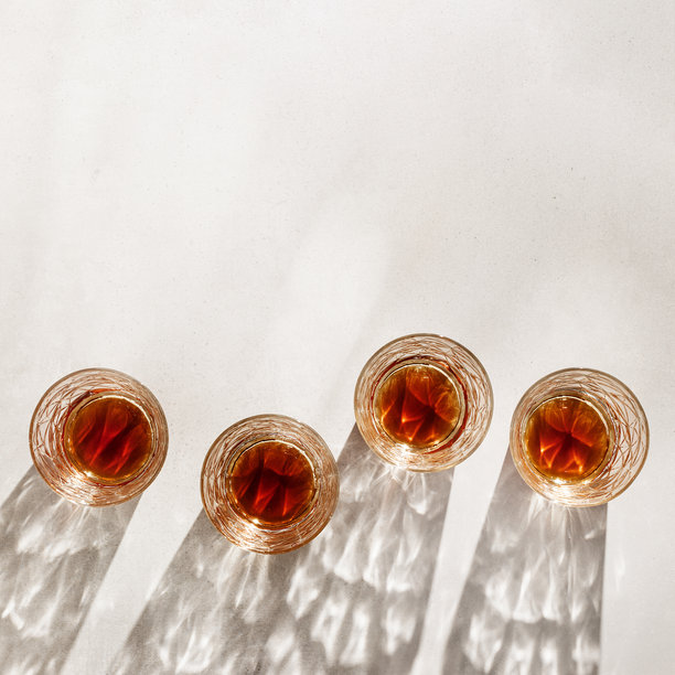 米色背景上的威士忌杯，阴影与阳光反射，简约风格的中性色照片，夏季静物的美学俯视图，透过水晶杯的折射光，光晕效果图片下载