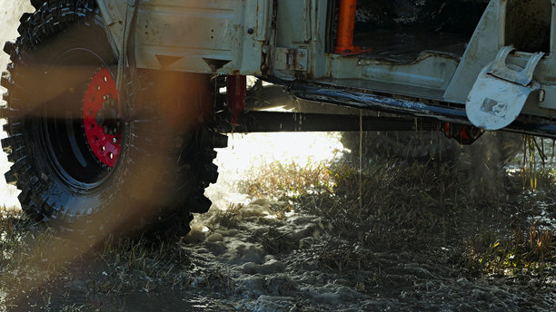 红边轮胎的汽车部分浸没在泥水中，水滴四溅。比赛后清洗越野车。图片下载