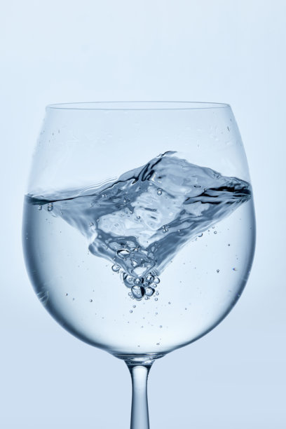 清晰的高脚杯中水流动的特写照片，展示了水的运动和气泡，背景简约。样机。图片下载