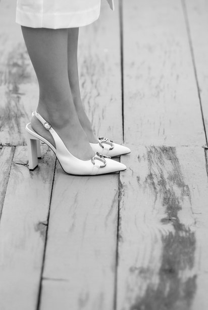 黑白照片中，穿着白鞋的腿在木地板上。图片下载
