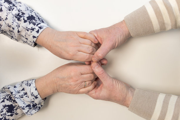 男性和女性的手，伴随着与年龄相关的皮肤变化，象征着牢固的纽带、关爱和支持。这张照片传达了家庭关系的温暖以及多年来积累的信任。图片下载