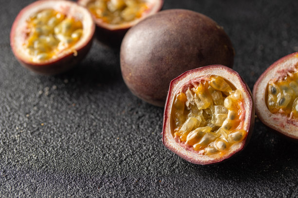 黑色背景下的百香果及其横截面，果肉多汁，满是种子。横幅照片，留有空白空间。图片下载