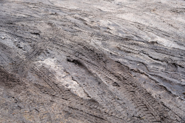 拍摄到的照片展示了粗糙土路上泥土中留下的详细轮胎痕迹，展现了经过车辆所形成的复杂图案和纹理。图片下载