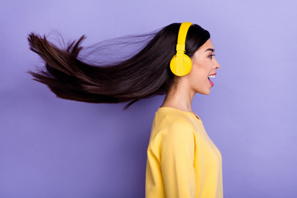年轻兴奋女孩侧面照片，耳机听着收音机，目光投向空旷的空间，背景为紫色。图片下载
