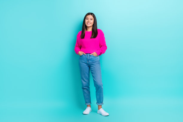 自信迷人的女士穿着粉色毛衣，微笑着走在青绿色背景前的全身照片图片下载