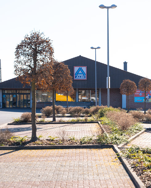 德国巴德赫斯费尔德，2025年3月2日，拍摄于一个阳光明媚的春天。照片展示了商店建筑、标志性的蓝红色标志，以及一个没有汽车的宽敞停车场。图片下载