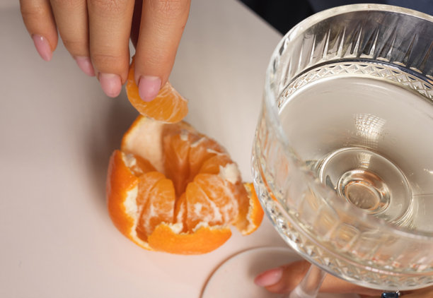 美丽的女人吃着橘子片，喝着气泡酒，并在涂有黄油的面包上放红鱼子酱。不同角度的照片，女孩穿着节日裙子庆祝某个特别时刻。新年快乐或生日快乐。图片下载