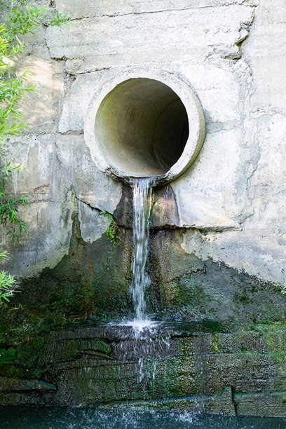 污水通过一根大型混凝土管道流入湖泊或河流。垂直照片图片下载