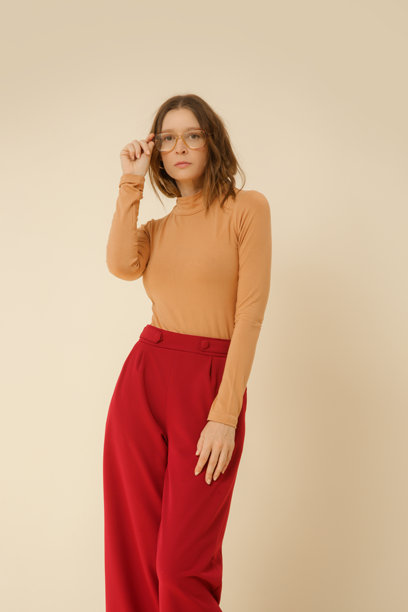 一系列年轻女性模特在摄影棚拍摄的照片，穿着简单而美丽的服装，米色高领上衣和红色宽腿裤。图片下载