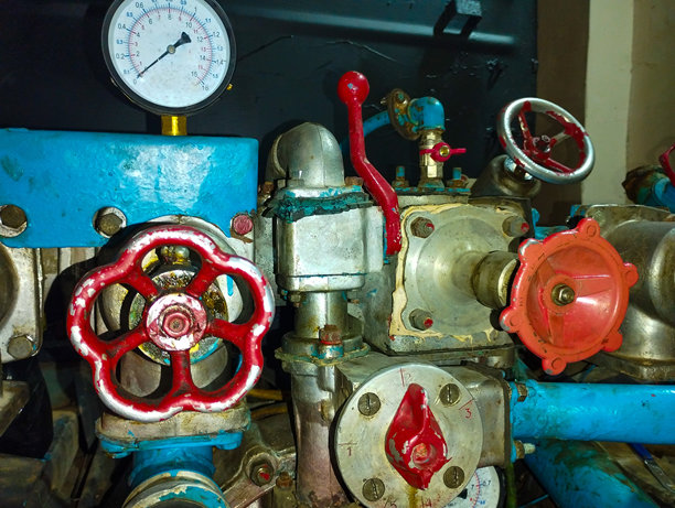 这张照片展示了工业设备的特写，包含压力表、阀门和管道。设备有多种颜色：蓝色、红色和银色。压力表上显示了刻度和指针。图片下载