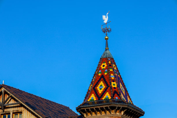 这张照片展示了一座建筑塔楼的特写，屋顶上铺有鲜艳的瓷砖。屋顶的瓷砖呈现出几何图案，色彩斑斓。图片下载