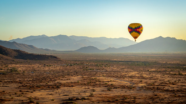 五彩斑斓的热气球在亚利桑那州凤凰城的索诺兰沙漠上空飞行。照片拍摄于日落时分的晴朗日子。图片下载