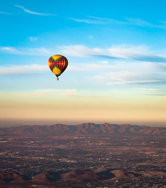 五彩斑斓的热气球在亚利桑那州凤凰城的索诺兰沙漠上空飞行。照片拍摄于日落时分的晴朗日子。图片下载